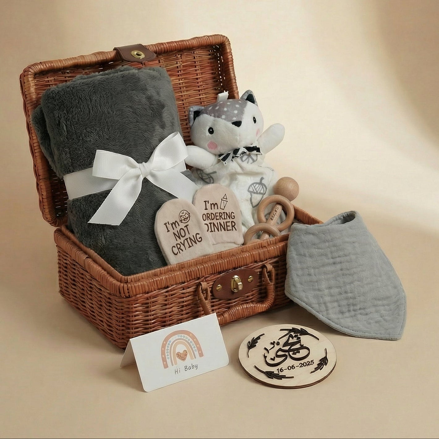Baby gift basket with plush toy, blanket, and items on a beige background