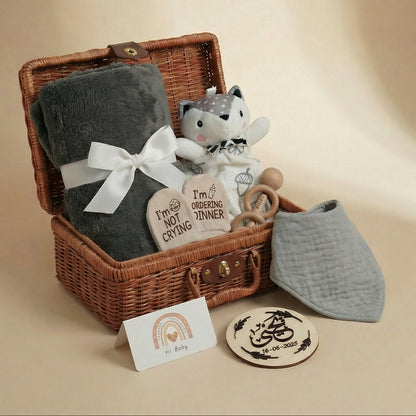 Baby gift basket with plush toy, blanket, and items on a beige background